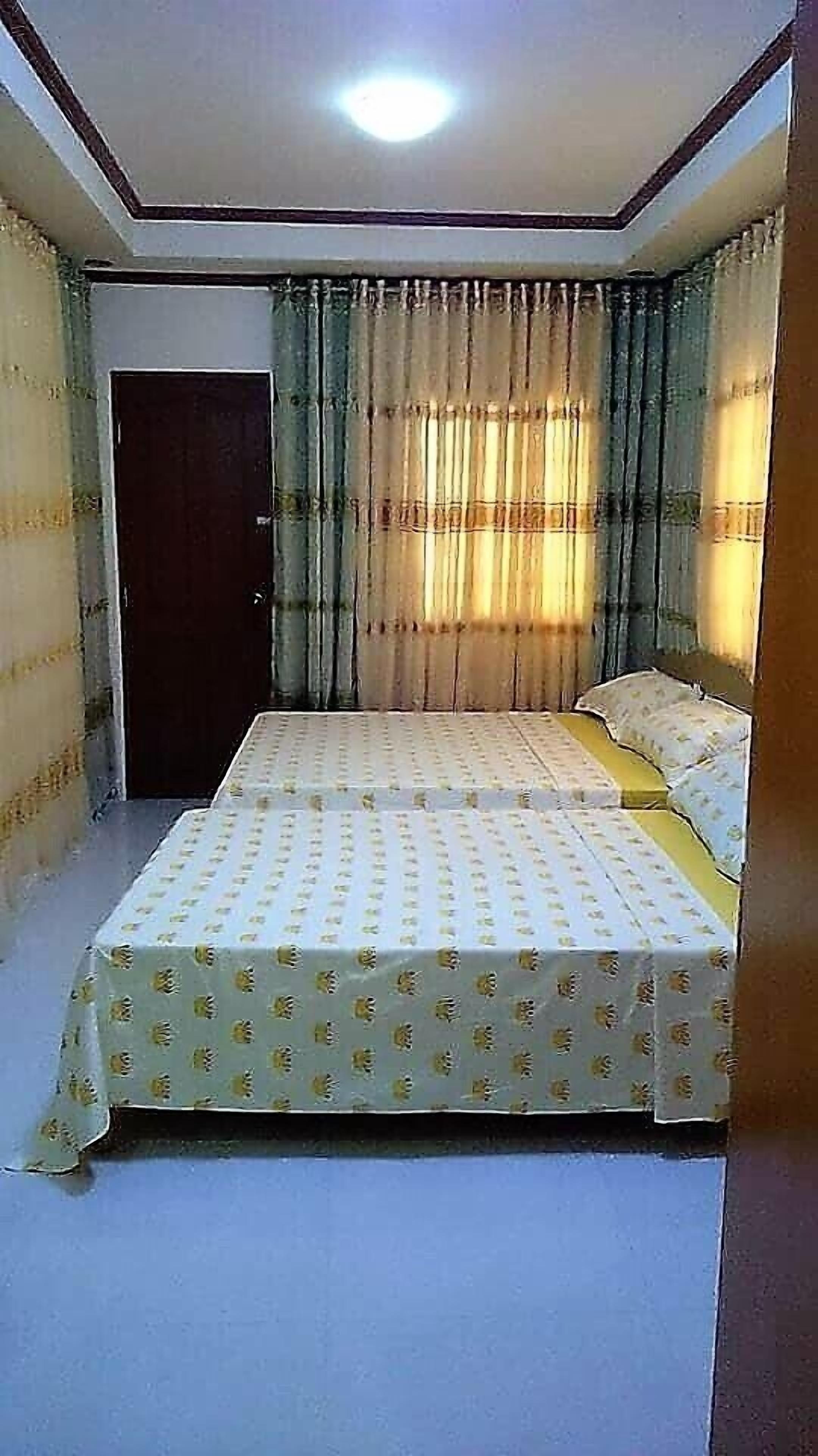A room with two beds, a door, and curtains.
