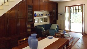 A dining area with a wooden table, chairs, and a blue vase. There is a staircase leading to another level. - Villa delle Sirene (Garda)