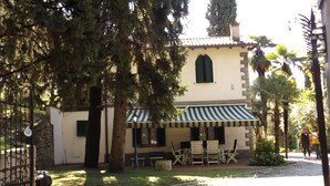 A building with a striped awning, outdoor seating, and a stone wall. - Villa delle Sirene (Garda)