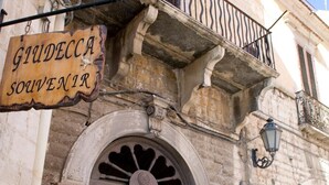 Un bâtiment sur lequel on peut lire l’inscription « SOUVENIRS DE GIUDECCA » et dont la porte est marquée du mot « APPARTEMENT ».