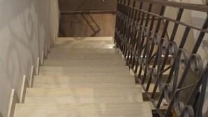 Un escalier avec une rampe métallique menant à un palier.