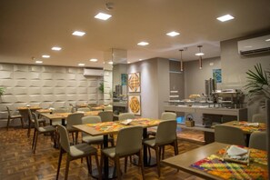 A modern dining area with wooden tables and chairs, a buffet station, and a patterned wall. - Amenit Hotel (Maceió)