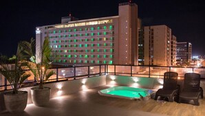 A rooftop pool area with a view of a hotel building in the background. - Amenit Hotel (Maceió)