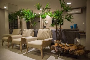 Una sala de estar moderna con tres sillones color beige, un sofá gris y una mesa de centro con objetos decorativos.