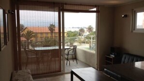 A balcony with a table and chairs, a sofa, and a TV. - 9.- HNA Mirador El Faro (La Serena)