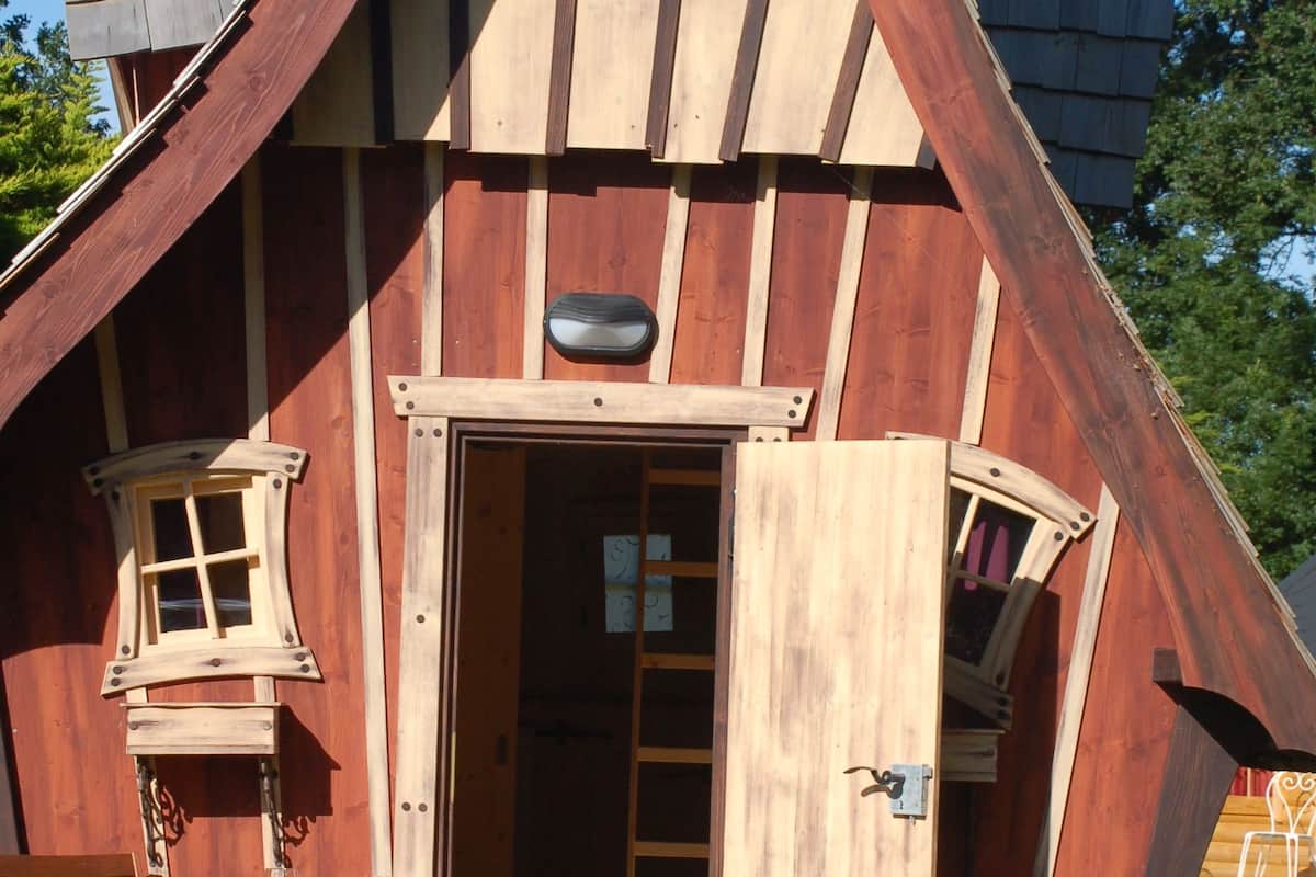 Een houten huis met schuin dak, een voordeur en een klein raam.