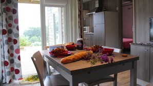 Een eetruimte met een gedekte tafel, een keuken op de achtergrond en uitzicht op het buitengebied.