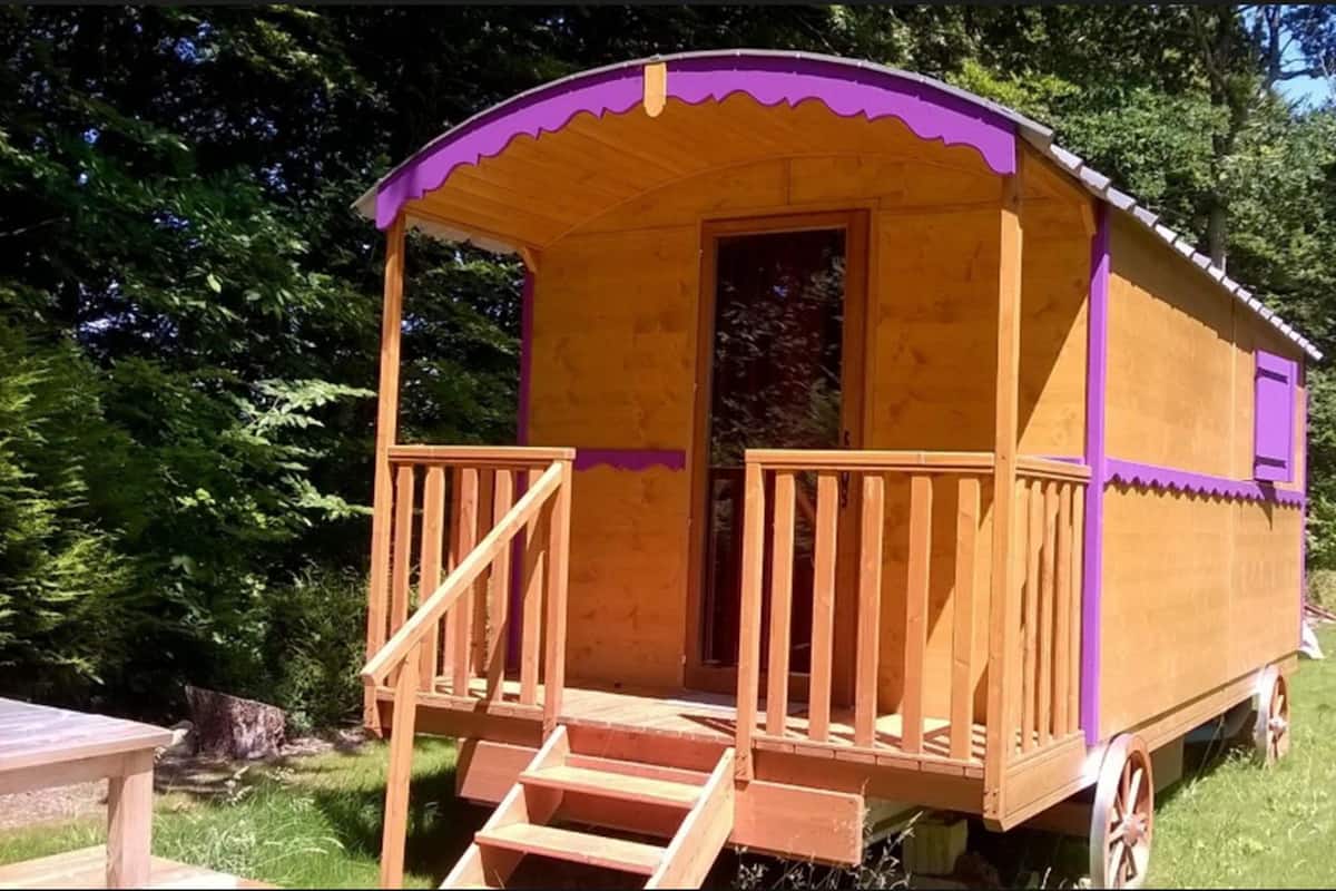 Een houten gebouw in de stijl van een koets met een veranda en een trap naar de deur.