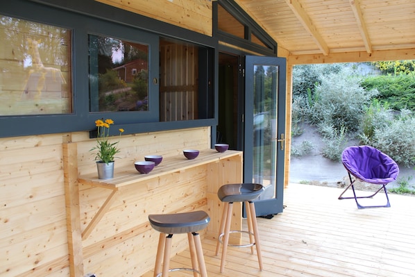 A wooden deck with a bar area, two stools, and a purple chair. - Insolites Du Camping De Trezulien (Douarnenez)