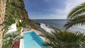 Una piscina con vista al océano y un acantilado rocoso.