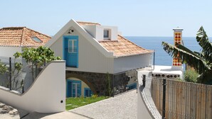Un edificio costero con una puerta azul, un arco de piedra y vistas al mar.