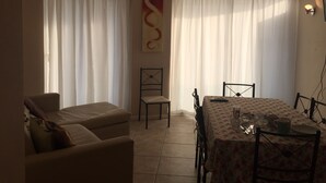 Un coin repas avec une table dressée pour quatre personnes, un canapé et un fauteuil.