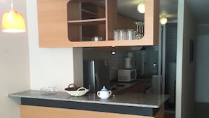 Une cuisine moderne avec un plan de travail en bois, un four encastré et un four à micro-ondes. Deux luminaires suspendus sont fixés au-dessus du plan de travail.