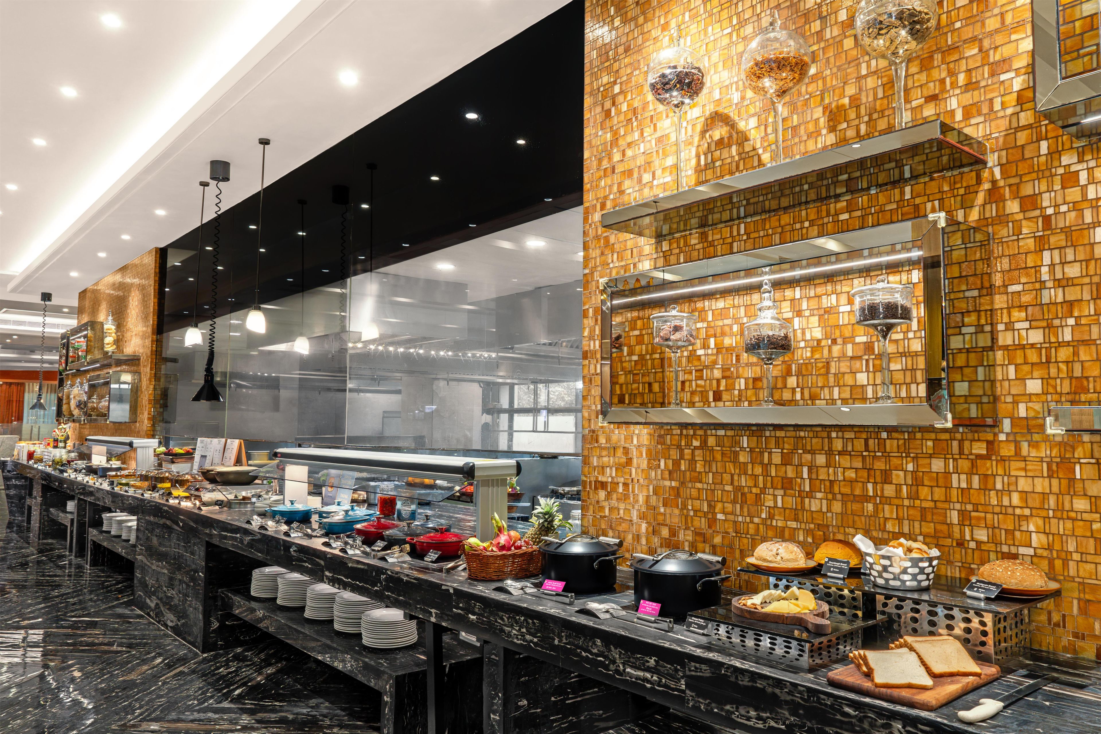 A buffet setup with various food items and condiments, a marble countertop, and a tiled backsplash.