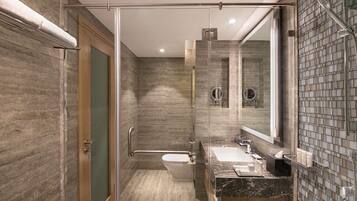 Une salle de bain moderne dotée d’une douche à parois de verre, de toilettes et d’un lavabo avec un plan de travail en marbre.