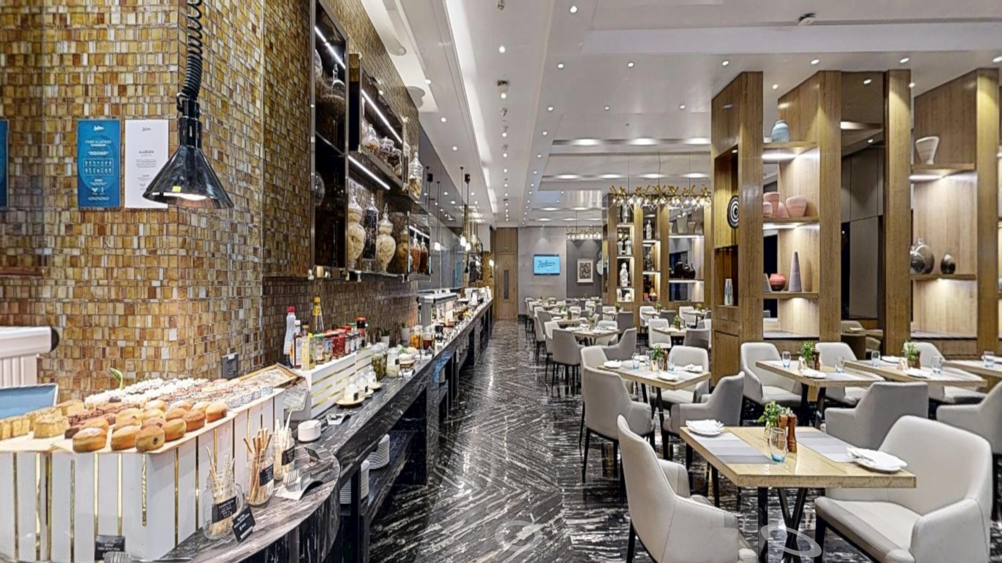 Un restaurant doté d’un long comptoir, de plusieurs tables et où une grande variété de plats est exposée.