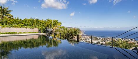 Una piscina infinita con vistas claras al océano y un paisaje urbano de fondo.