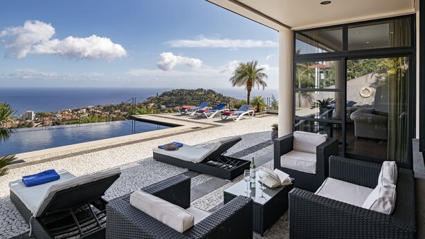 Ein moderner Außenbereich mit Liegeplätzen, Pool und Blick auf das Meer und die Stadt.