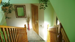 Eine Treppe mit Holzwertlauf, einer Tür und einem Spiegel an der Wand.