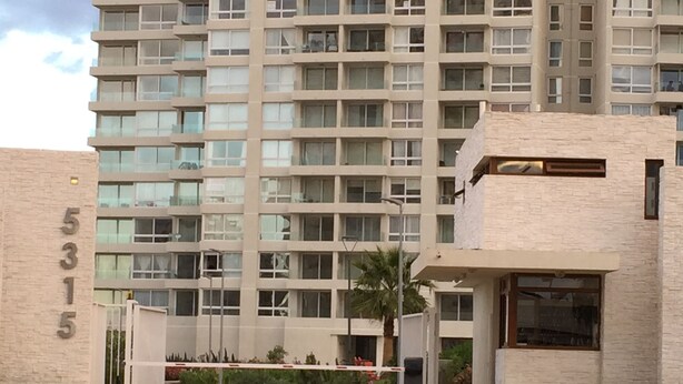 A multi-story building with a modern design, featuring a large entrance with a gated driveway and a well-maintained landscaped area with palm trees. - 13.- HNA Marina Sol 1 (Coquimbo)