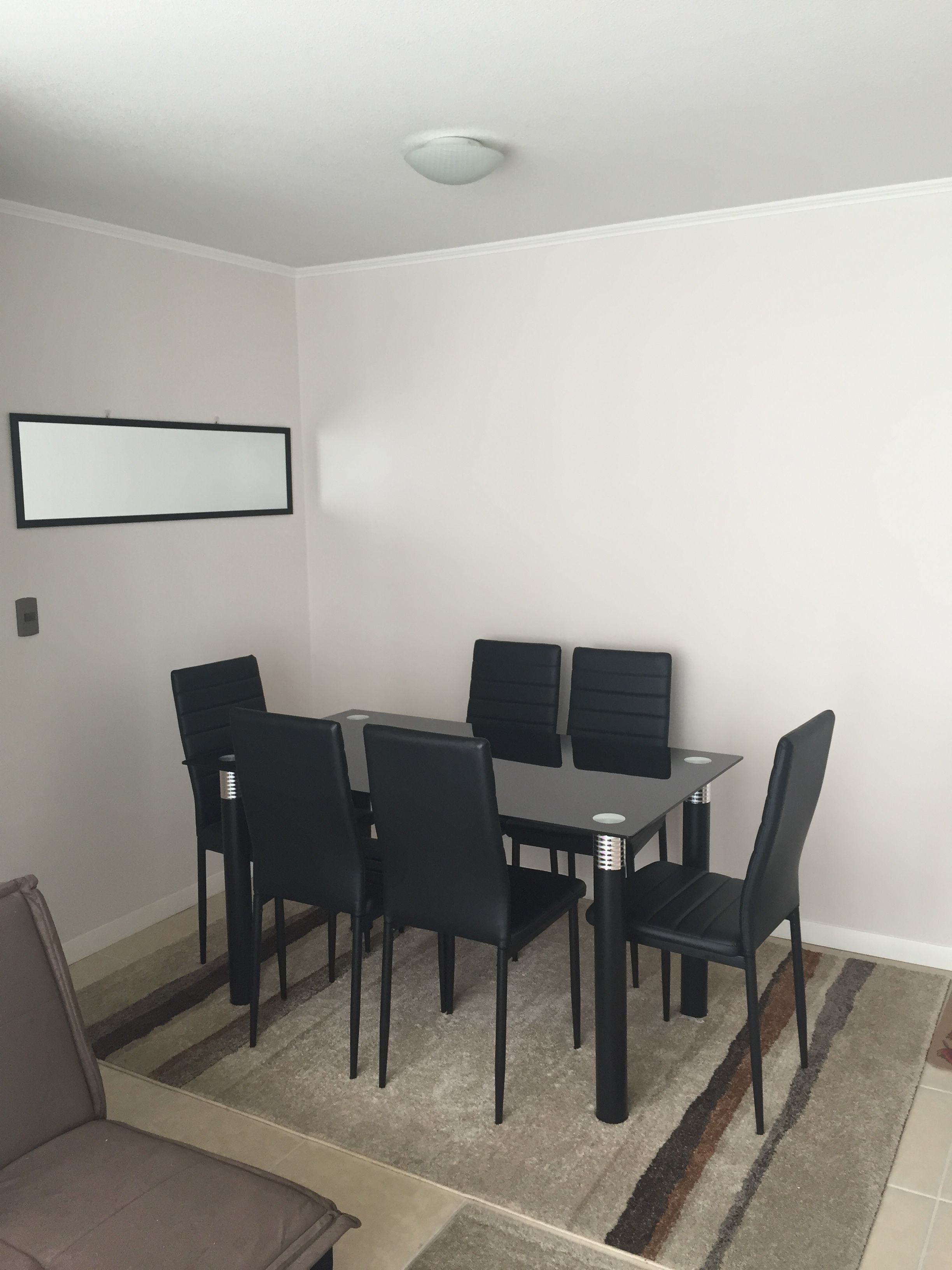A conference room with a rectangular table, six black chairs, a brown sofa, and a white ceiling light.