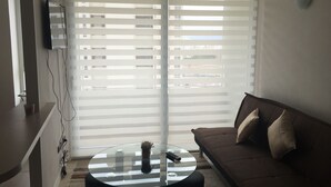 A living room with a glass coffee table, a brown sofa, and a TV mounted on the wall. - 13.- HNA Marina Sol 1 (Coquimbo)