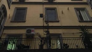 Ein mehrstöckiges Gebäude mit Balkonen, Klimaanlagen und einem Metallzaun.