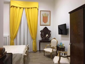 A hotel room with a bed, a chair, a desk, a television, and a coat rack. - Royal Gismonda (Naples)