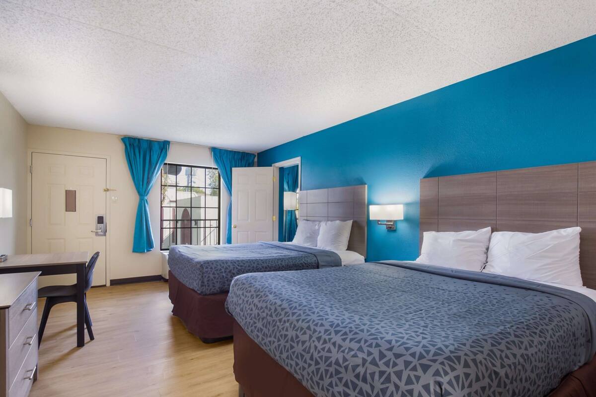 A hotel room with two beds, a desk, and a chair.