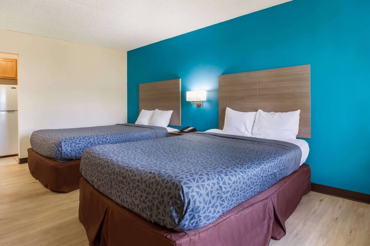 A hotel room with two beds, a blue wall, and a wooden headboard.