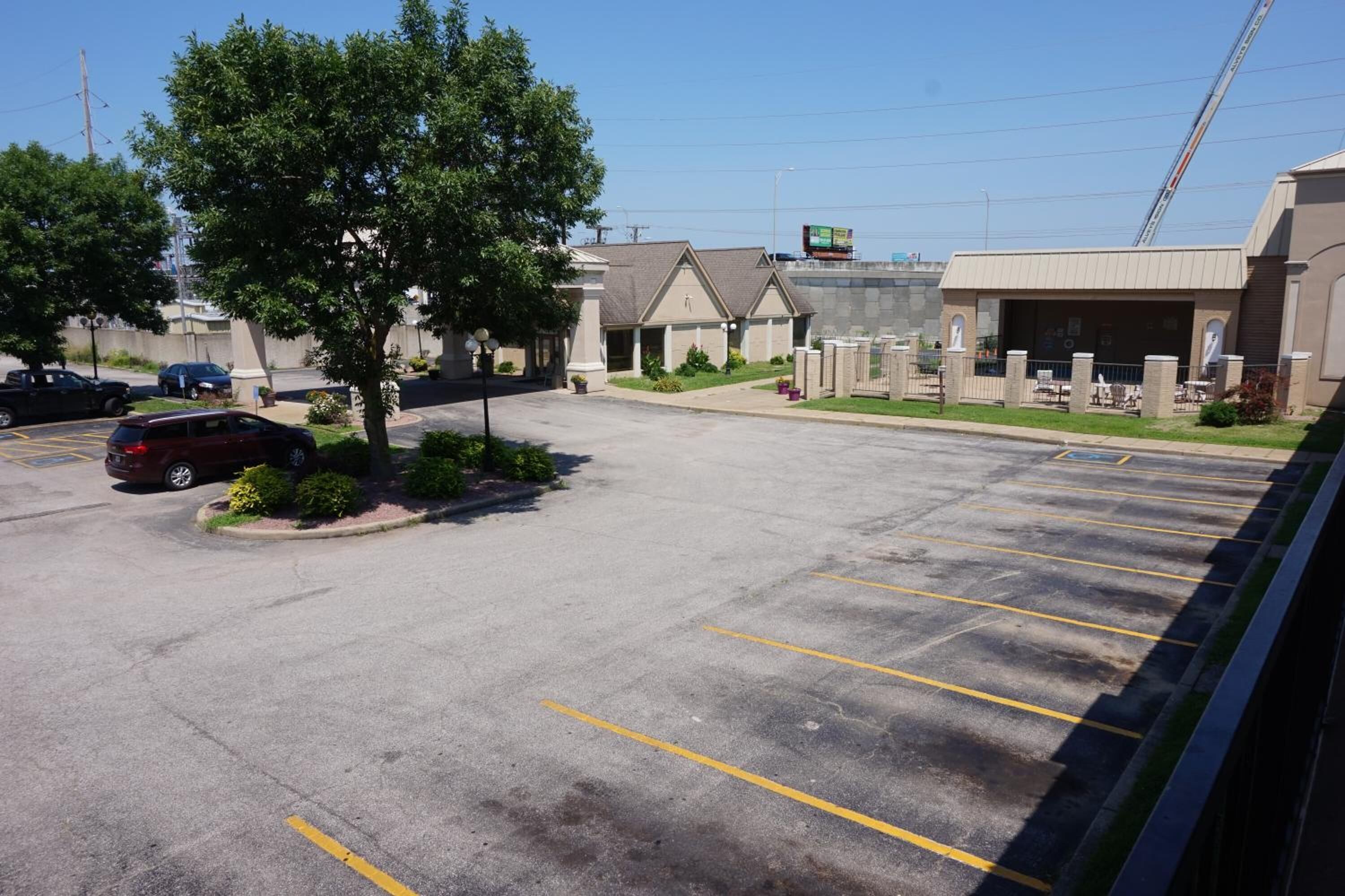 A parking lot with a few cars, a building with a covered area, and a tree.