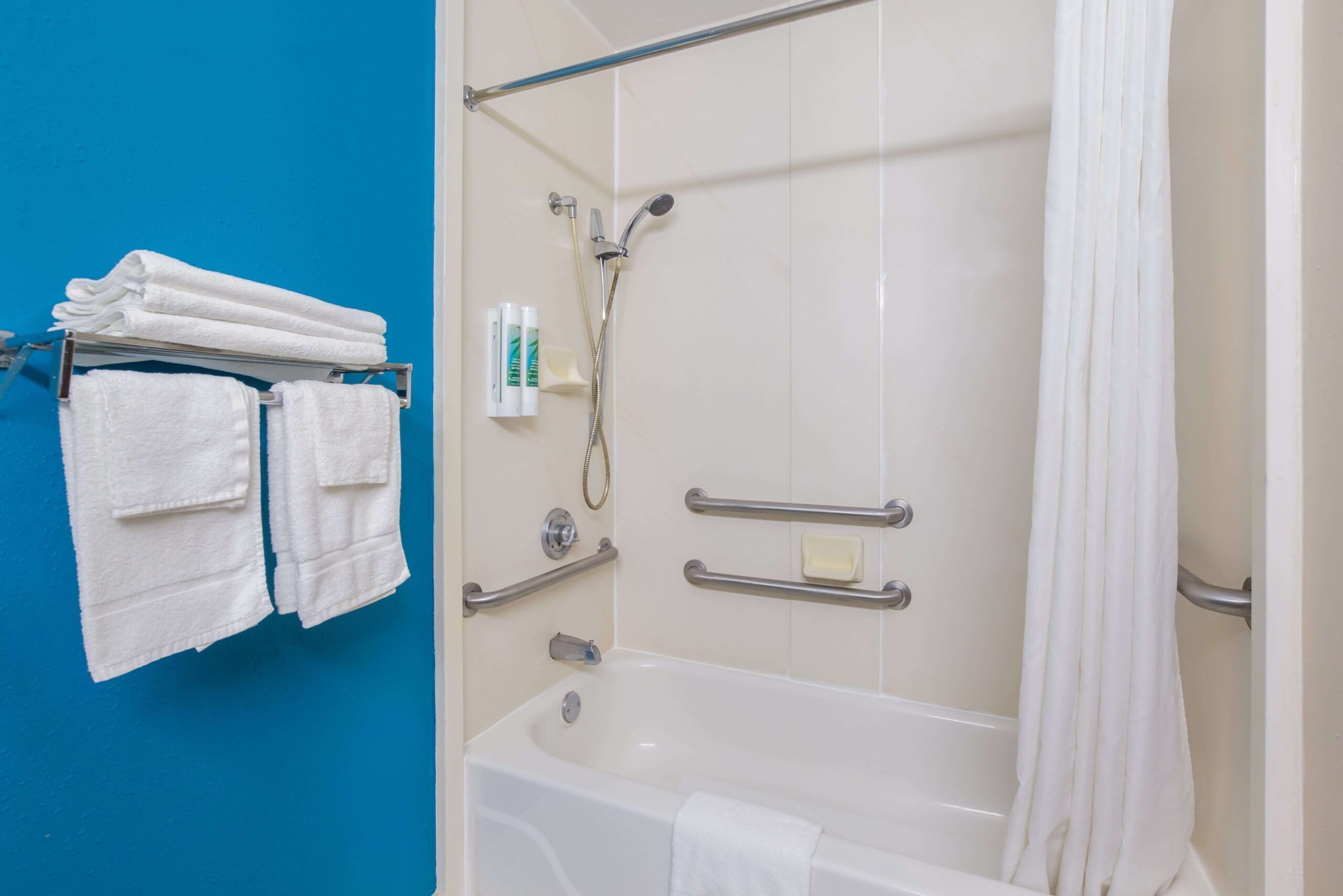 Ein Badezimmer mit einer Badewanne, einer Dusche und einem Handtuchhalter mit Handtüchern.