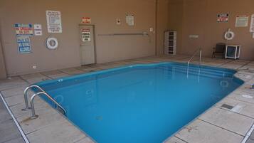 A swimming pool with safety signs, a diving board, and a lifebuoy.