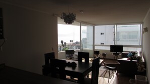 Una sala de estar moderna con comedor, ventanas amplias y vista a la ciudad.