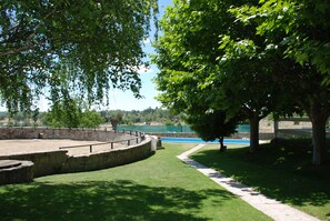 A park with a stone amphitheater, a grassy area, and a view of a body of water. - B&B Yeguada la parrilla (El Escorial)