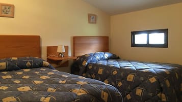 A hotel room with two beds, a nightstand, a lamp, and a window.