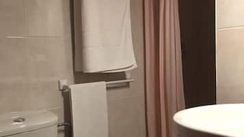 Un baño con inodoro, lavamanos, bañera y cortina de ducha.