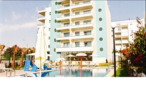 A modern hotel with a pool area, including lounge chairs and umbrellas. - L'escale Suites Residence Hoteliere (Mohammedia)