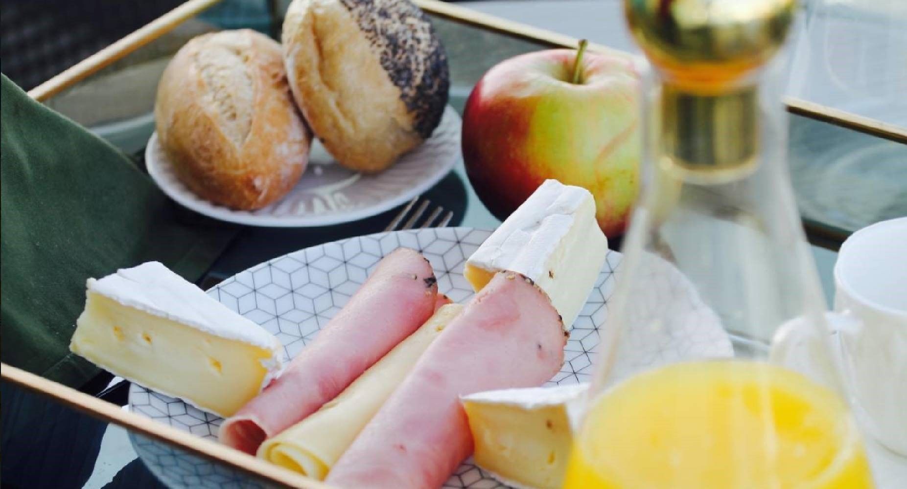A tray with ham, cheese, an apple, and a glass of orange juice.