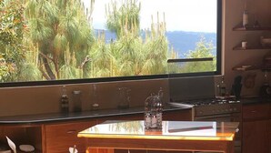 Una cocina con un ventanal grande, una mesa de madera y una planta en maceta.