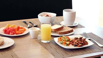 Una mesa de desayuno con platos de comida, un vaso de jugo y tazones.