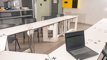 Un espacio de oficina moderno con mesas blancas, una computadora portátil sobre una mesa y un adorno de pared amarillo y negro.