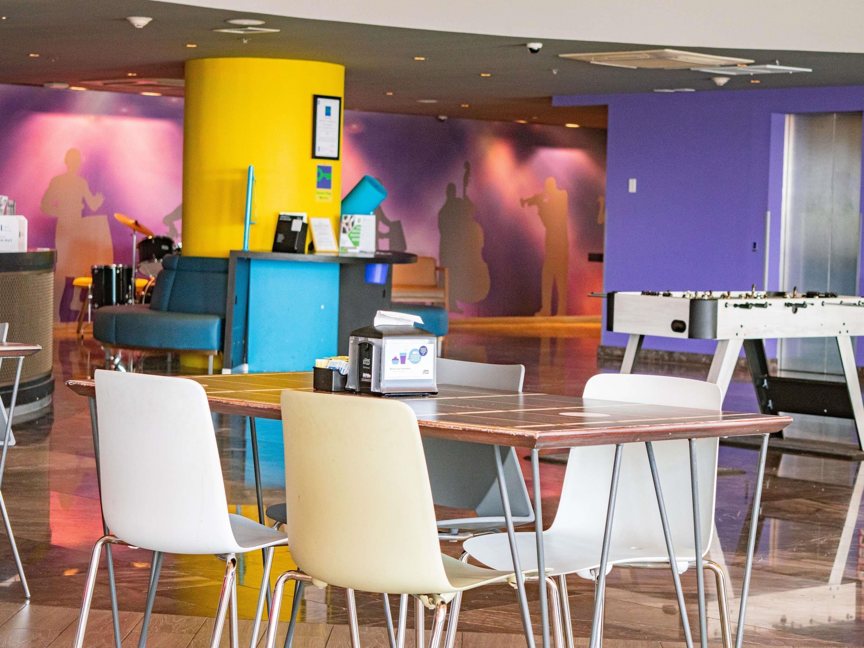 Un espacio lounge moderno con una mesa de fútbol, asientos y una barra con una máquina de café.