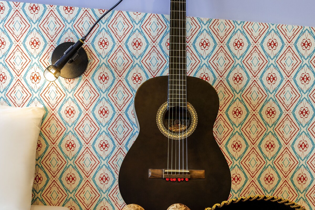 A guitar, a sombrero, and a decorative wall with a geometric pattern.