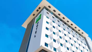 Un moderno edificio de hotel con fachada geométrica, un llamativo letrero con la palabra 'HOTEL' y un cielo azul despejado al fondo.