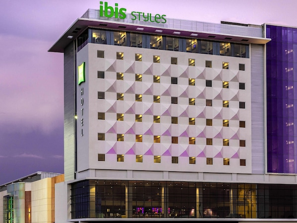 A modern hotel building with a geometric facade, large windows, and a prominent 'ibis Styles' sign. - ibis Styles Merida Galerias (Mérida)