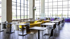 A spacious indoor area with large windows, multiple tables and chairs, and a view of the outdoors. - ibis Styles Merida Galerias (Mérida)