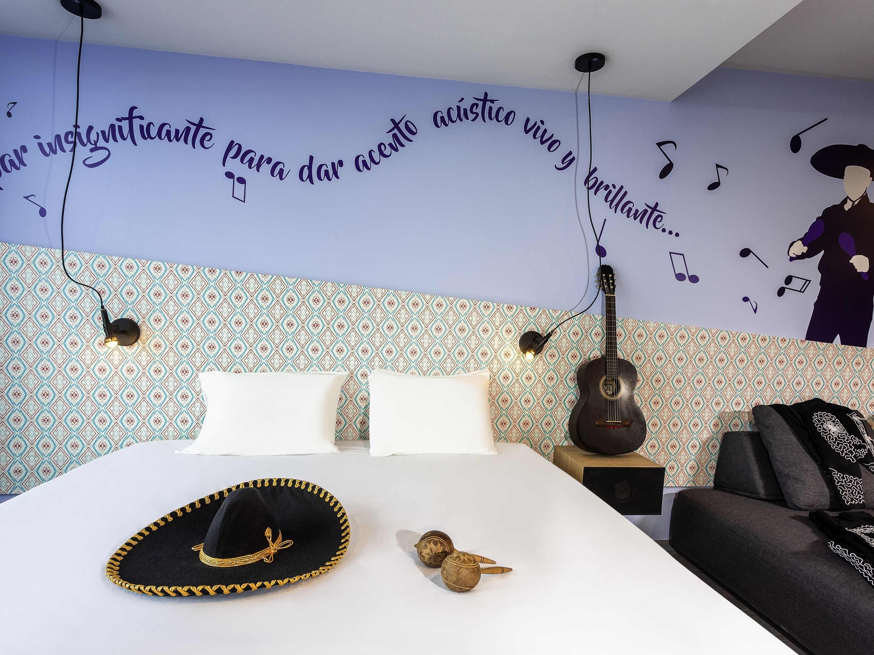 Ein Schlafzimmer mit einem Bett, einer Gitarre, einem Sombrero und einer Wand mit Musikmotiv.