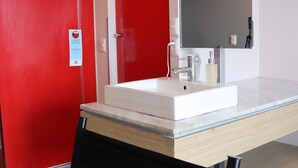 Ein modernes Badezimmer mit Waschbecken, Spiegel und roten Wänden.