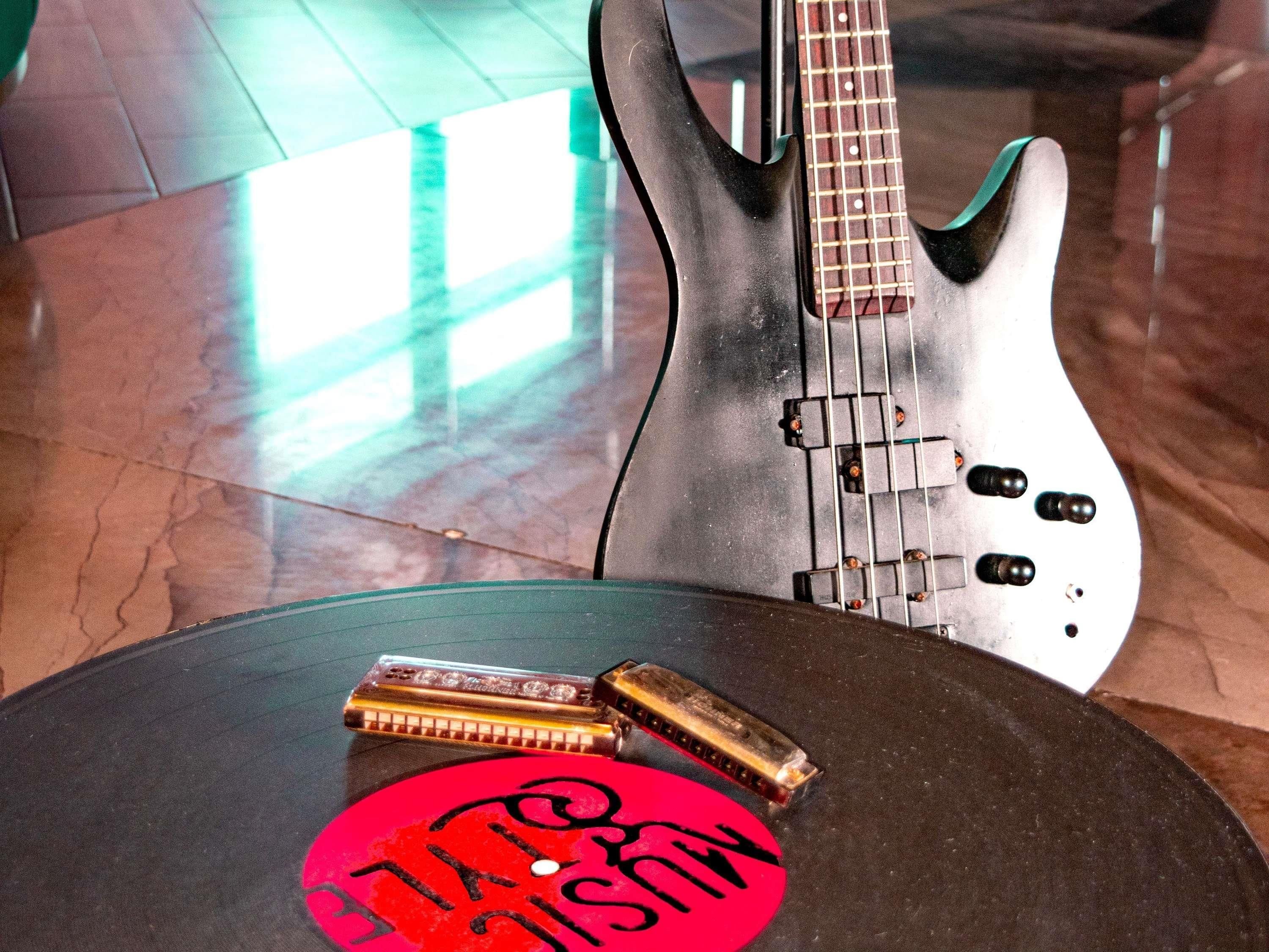 Una chitarra, un'armonica e un adesivo rosso con testo nero su un tavolo rotondo.